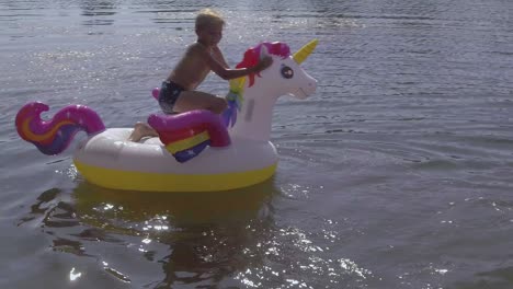 Sommerjunge-Reitet-Auf-Einem-Aufblasbaren-Einhorn-Im-Wasser