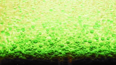 Makroaufnahme-Dunkelgrüner-Blasen,-Die-Sich-Auf-Dem-Wasserboden-Bilden,-Mit-Einem-Leuchtend-Gelben-Hintergrund