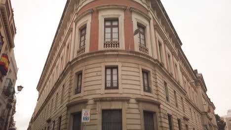 Edificio-De-La-Hemeroteca-Municipal-En-Sevilla,-Incline-Hacia-Abajo-A-La-Gente-Bajo-La-Lluvia