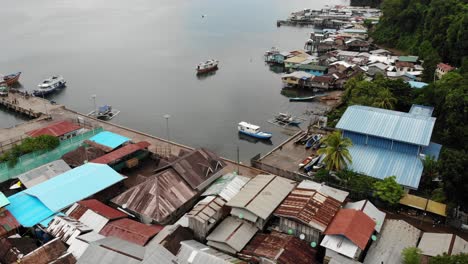 4K-aerial-panning-shot-of-port-with-boats-flying-over-homes-and-buildings-in-Balabac-Palawan,-Philippines