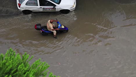 Man-with-a-scooter-vespa-stuck-in-the-sewage-of-a-flooded-street-after-a-strong-storm-hit-the-city-of-Kusadasi-in-Turkey