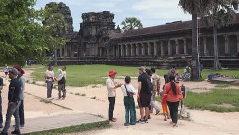 Turistas-Parados-Afuera-De-Angkor-Wat-Hablando-Con-Guía-Turístico
