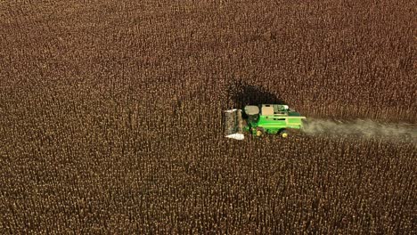 Aerial-drone-shot-of-John-Deere-combine-tractor-harvesting-sunflower-seeds-during-summer-evening-in-Bulgarian-rural-countryside