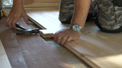 Close-shot-of-man-laying-new-pinewood-floor-on-top-of-insulation