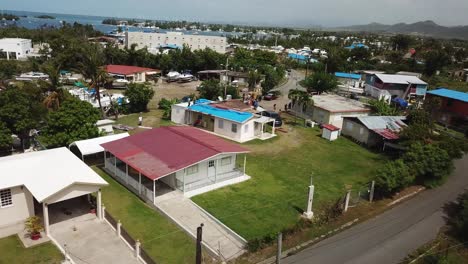 Pull-Back-Aerial-View-of-People-on-Rooftop-Of-House-Working-on-Reconstruction-After-Hurricane-Damage