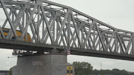 Un-Tren-Interurbano-Holandés-Pasa-Por-El-Puente-Ferroviario-De-Hedel-En-Los-Países-Bajos.