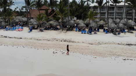 Mujer-Caminando-Por-Una-Hermosa-Playa-Tropical,-Toma-Panorámica-Aérea