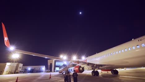 Personas-Con-Máscaras-Faciales-Para-Corona-Caminando-Fuera-Del-Avión-Por-La-Noche-En-El-Aeropuerto-Kayseri-Erkilet-En-Turquía-Con-Un-Avión-De-La-Aerolínea-Corendon-Estacionado-En-La-Oscuridad---Bloqueo-Pandémico-Del-Virus-Covid-Volando