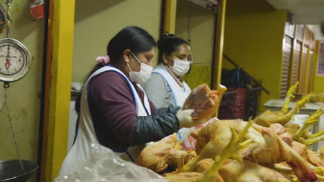 A-woman-using-a-cleaver-to-cut-up-a-raw-chicken-in-a-market-in-Peru-during-the-COVID-19-pandemic
