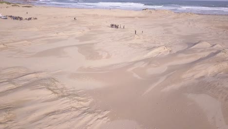 Aerial-pull-back-reveals-a-wide-sandy-Stockton-Beach-next-to-a-sand-dunes-desert-at-Port-Stephens,-Sydney,-Australia