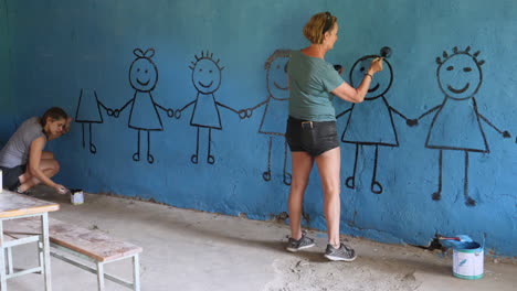 Junge-Frau-Malt-Kinderfiguren-In-Die-Klassenzimmerwand-Der-Schule