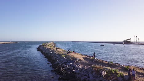 Mehrere-Gruppen-Von-Menschen-Genießen-Einen-Sonnigen-Spätnachmittag-Auf-Einem-Wellenbrecher-In-Long-Beach,-Kalifornien