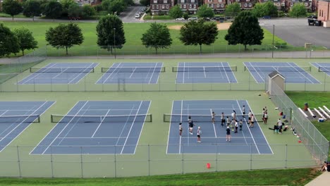 Children-wearing-masks-practice-tennis-on-court,-coronavirus-covid-19-pandemic-impacts-student-athletics