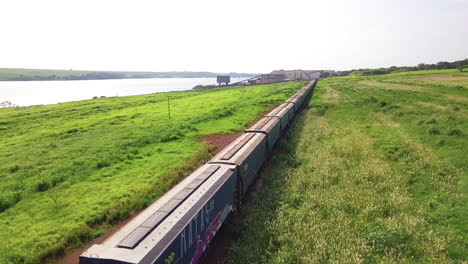 Tren-Y-Muchos-Vagones-Esperando-Para-Cargar-Grano-En-Un-Puerto-Junto-A-Un-Hermoso-Río.