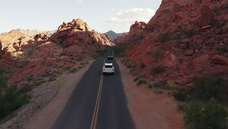 Rolls-Royce-and-convertible-Ferrari-driving-through-the-canyons-in-the-Valley-of-Fire,-Nevada