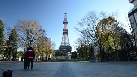 Asiatischer-Tourist,-Der-Fotos-Macht-Und-Vor-Dem-Fernsehturm-Von-Sapporo-Posiert