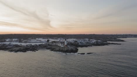 Slow-AERIAL-SLIDE-past-Portland-Head-Light,-winter-sunset