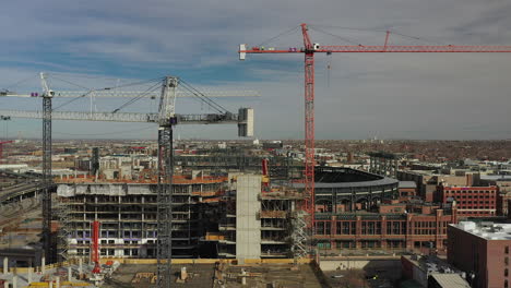 Aufsteigende-Luftdrohnenaufnahmen-Mehrerer-Baukräne-Mit-Coors-Field-Im-Hintergrund,-In-Denver,-Colorado