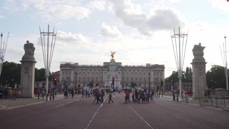 Front-view-of-Buckingham-Palace-in-London-with-people-crossing-The-Mall-Street,-wide-angle-static-shot