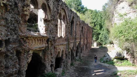 Ruinas-Antiguas-Rodeadas-De-Bosque-En-Ucrania-Con-Una-Mujer-Caminando-Al-Lado