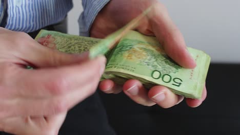 Young-businessman-counting-Argentine-cash-money-"pesos".-Close-up