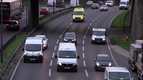 Ein-Zeitraffer-Mit-Blick-Auf-Fahrzeuge-Mit-Scheinwerfern,-Die-An-Einem-Kalten-Novembertag-In-Der-Abenddämmerung-Auf-Einer-Dreispurigen-Straße-Fahren-Und-Unter-Einer-Überführung-Hindurchfahren