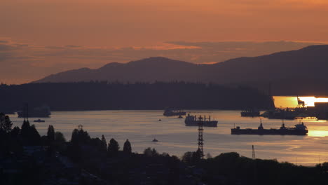 Cargo-Freight-Ships,-Barge-Anchored-And-Travelling-On-The-Ocean-Near-The-Vancouver-Harbour,-View-From-Burnaby-City,-Canada-During-Sunset