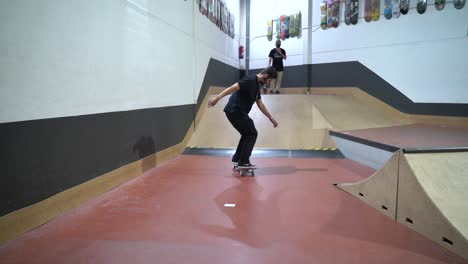 Männlicher-Skateboarder-Macht-360-Grad-Stunt-Im-Indoor-Skatepark