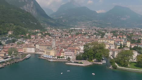 Aerial-drone-view-of-the-beautiful-Riva-Del-Garda-town-and-lake-garda-surrounded-by-the-italian-alps-in-the-summer-time