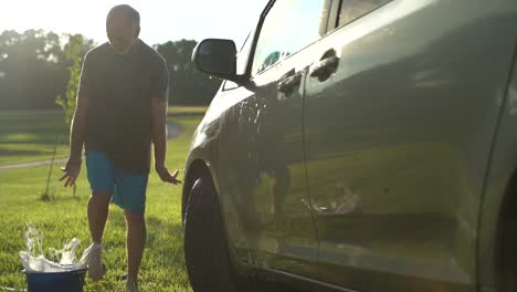 Dancing-funny-man-washing-car-with-backlit-sun-in-slow-motion