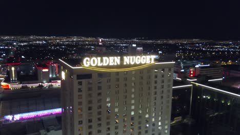 4K-AERIAL:-Aerial-shot-going-backwards-from-the-Golden-Nugget-Hotel-and-Casino-in-Las-Vegas-with-the-city-lights-in-background-at-dusk