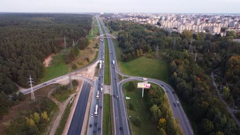 Drone-ascending-with-the-view-of-Kaunas-city-residential-district-over-the-A1-highway-with-heavy-traffic-and-pedestrian-bridge-in-the-distance