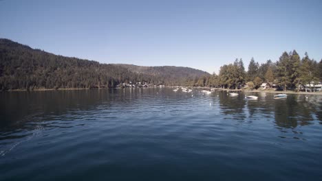 Drohnen-4K-Aufnahmen-Von-Friedlichen-Schnellbooten,-Die-An-Einem-Sonnigen-Tag-In-Einem-Von-Bergen-Umgebenen-Muschelkultus-See-Freizeitbeschäftigung-Betreiben