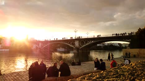 Timelapse-Del-Atardecer-Dorado-Con-Gente-Junto-Al-Puente-De-Triana-En-Sevilla,-España