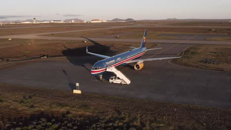 Aerial-flying-towards-old-Icelandair-aircraft-parked-in-open-field-at-airport