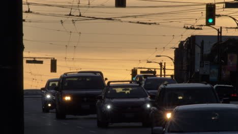 Abendlicher-Straßenverkehr-In-Einer-Modernen-Stadt-Mit-Fahrenden-Autos,-Autoscheinwerfern-Und-Ampeln-Am-Abend