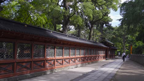 Japanese-business-man-wearing-facemask-during-corona-crisis-walking-next-to-typical-wall-of-Japanese-temple