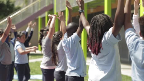 Grundschüler-Machen-Yoga-Auf-Gras,-Entlang-Einer-Reihe-Von-Kindern,-Zeitlupe