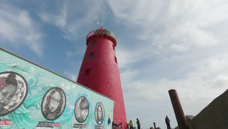 Los-Turistas-Que-Visitan-El-Faro-De-Poolbeg-Con-Preciosos-Murales-En-Wal-En-Poolbeg,-Dublín,-Irlanda