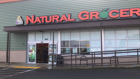 Lady-Customer-In-Face-Mask-Walk-Towards-Automatic-Sliding-Doors-Of-Natural-Grocers-At-Daytime-In-Coos-Bay,-Oregon