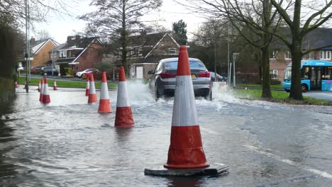 Storm-Christoph-cars-and-van-driving-rainy-flooding-village-road-splashing-street-cones