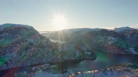 Big-bright-sun-with-massive-sun-rays-setting-over-mesmerizing-Veafjorden---Norway-winter-landscape-panning-shot