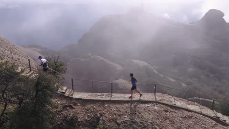 Aerial-view-of-runners-climbing-Montserrat-mountain-during-marathon-competition,-circle-pan