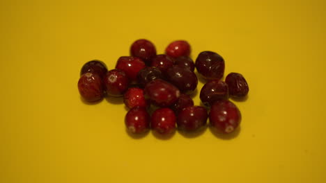 Close-Up-Pan-of-Cranberries-on-a-Yellow-Backdrop