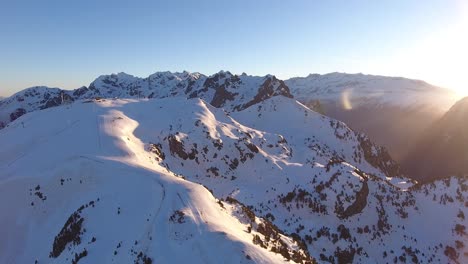 Snowed-Alps-summit-in-the-Chamrousse-peaks-in-France-with-sunrise-rising,-Aerial-pan-left-shot