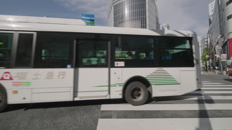 Different-Vehicles-Traveling-Across-Shibuya-Crossing-Against-High-Rise-Building-In-Tokyo,-Japan