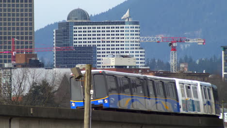 Expo-Line-SkyTrain-Turning-On-Curved-Track-With-Tower-Cranes-And-Buildings-In-Background-In-Vancouver,-British-Columbia,-Canada