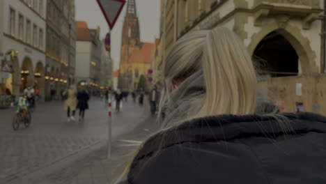 Beautiful-blond-girl-with-mask-walking-through-old-town-of-Muenster-City,close-up-shot