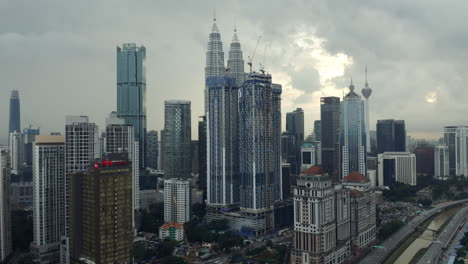 Toma-Aérea-De-Seguimiento-De-Las-Torres-Gemelas-Petronas-Y-El-Horizonte-De-La-Ciudad-De-Kuala-Lumpur-En-Malasia