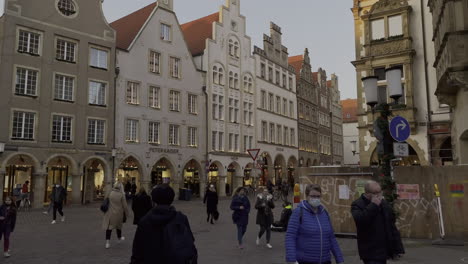 Slow-motion-shot-of-people-with-protection-mask-strolling-in-beautiful-city-square-of-Muenster,Germany